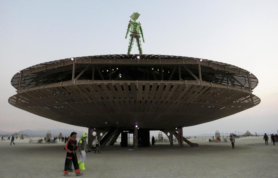 Participants walk past the effigy of the Man, seen at the center of the 2013 Burning Man arts and music festival in the Black Rock Desert of Nevada, August 29, 2013. The federal government issued a permit for 68,000 people from all over the world to gather at the sold out festival, which is celebrating its 27th year, to spend a week in the remote desert cut off from much of the outside world to experience art, music and the unique community that develops. REUTERS/Jim Bourg (UNITED STATES - Tags: SOCIETY) FOR USE WITH BURNING MAN RELATED REPORTING ONLY. FOR EDITORIAL USE ONLY. NOT FOR SALE FOR MARKETING OR ADVERTISING CAMPAIGNS. NO THIRD PARTY SALES. NOT FOR USE BY REUTERS THIRD PARTY DISTRIBUTORS