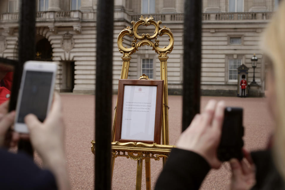 People take pictures of the notice on an easel in the forecourt of Buckingham Palace, London, Tuesday, May 7, 2019, placed on Monday to formally announce the birth of a baby boy to Britain's Prince Harry and Meghan, Duchess of Sussex. The as-yet-unnamed baby arrived less than a year after Prince Harry wed Meghan Markle in a spectacular televised event on the grounds of Windsor Castle that was watched the world over. (AP Photo/Tim Ireland)