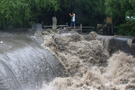 A man takes a picture of floodwaters in Las Pinas, Metro Manila as a storm sweeps across the main Luzon island, Philippines, September 12, 2017. REUTERS/Erik De Castro