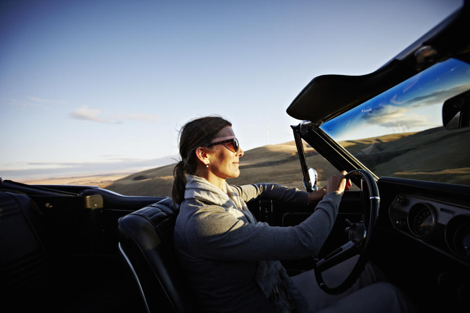 A woman driving convertible at sunset