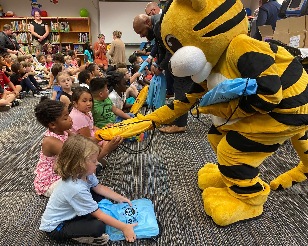 TJ, the mascot for the University of Missouri Children's Hospital, on Tuesday hands out full bookbags to students at Blue Ridge Elementary School.