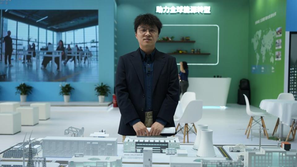 Man stands in front of model of buildings at energy expo