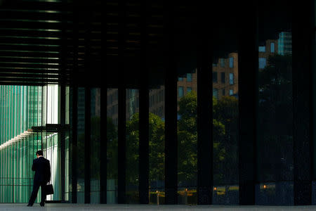 A businessman stands in front of an office building in central Tokyo, Japan, June 3, 2016. REUTERS/Thomas Peter/File Photo