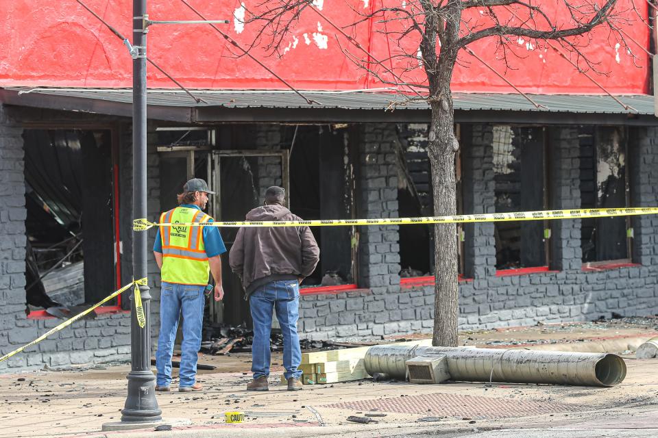 Workers survey the damage after a fire destroyed two downtown Kyle businesses in the wee hours of Thursday morning.