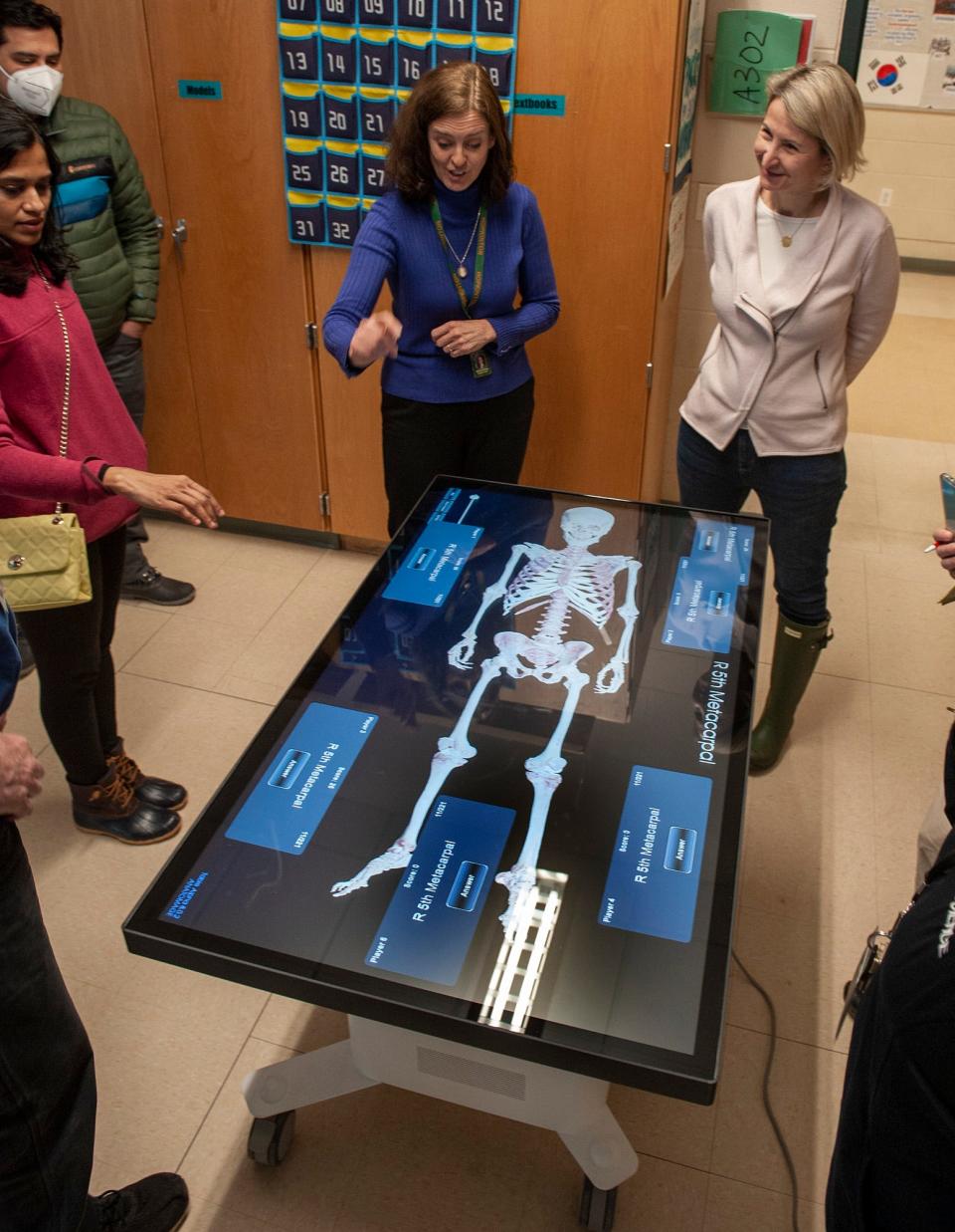 Marjorie Billeter, center, Hopkinton High School anatomy and physiology teacher, demonstrates the new Anatomage Table to Hopkinton Education Foundation President Chris Fredericks, right, and Nanhini Ponninathan, left, and Vijay Vanguri.