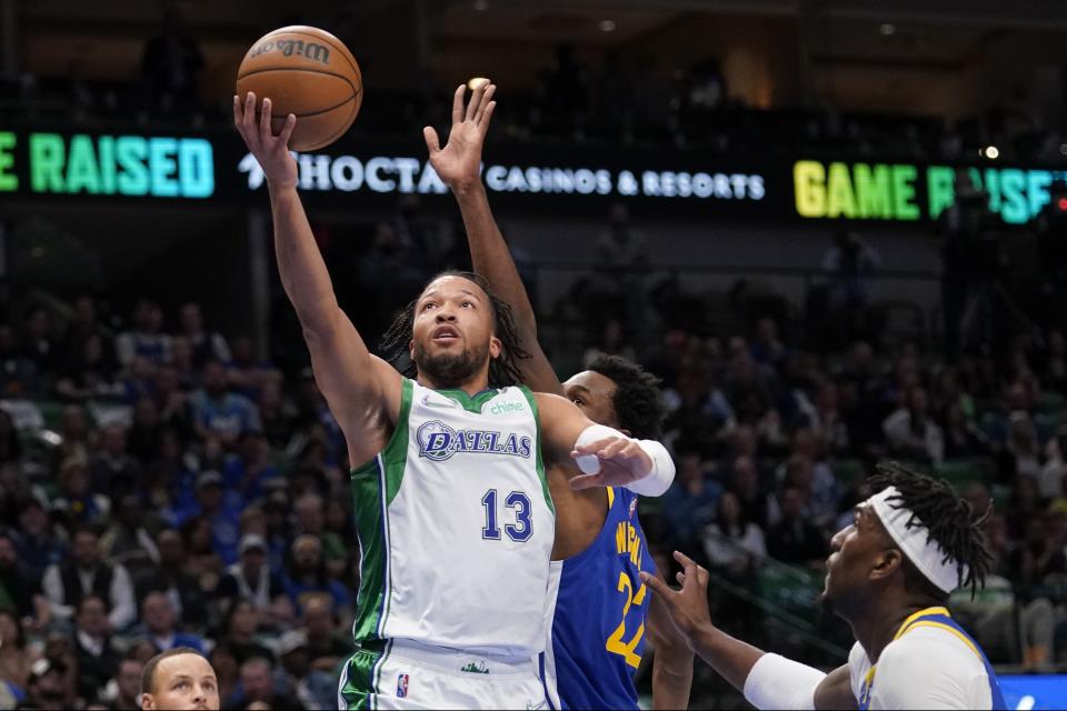 Dallas Mavericks guard Jalen Brunson (13) gets past Golden State Warriors forward Andrew Wiggins (22) for a shot in the first half of an NBA basketball game in Dallas, Thursday, March, 3, 2022. (AP Photo/Tony Gutierrez)