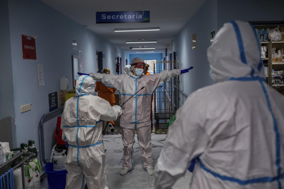 A medical team member is disinfected before leaving the COVID-19 ward at the Severo Ochoa hospital in Leganes, outskirts of Madrid, Spain, Friday, Oct. 9, 2020. At the peak of the first wave, ICU wards were given over to haste, desperation and even cluelessness about what to do. Now, a well-oiled machinery saves some lives and loses others to coronavirus, but without the doomsday atmosphere of March and April. (AP Photo/Bernat Armangue)