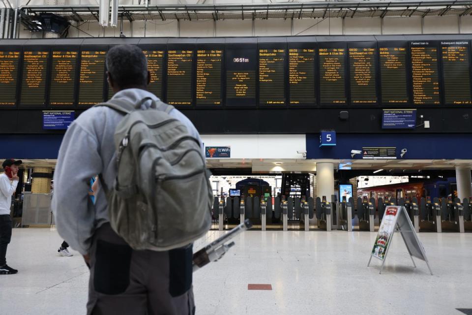 Passengers stand on the concourse viewing the departures board at Waterloo station (PA)