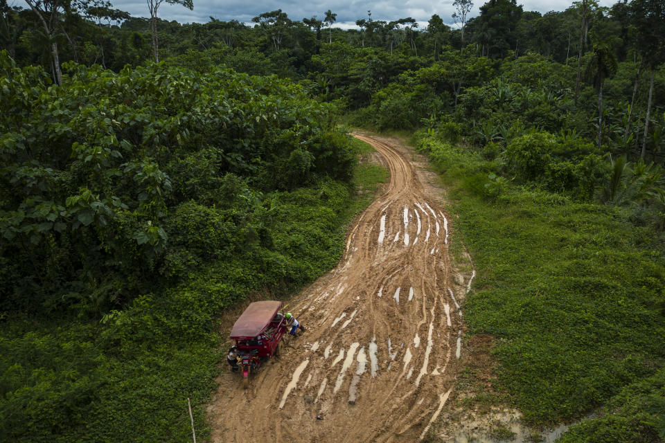 Muruis push a cargo tricycle stuck in the mud on the proposed path of a federal highway to be built from Iquitos to El Estrecho district, Nuevo Arenal, Peru, Tuesday, May 28, 2024. The highway project in an untouched area of the Peruvian Amazon is facing mounting opposition from Indigenous tribes, including the Murui. (AP Photo/Rodrigo Abd)