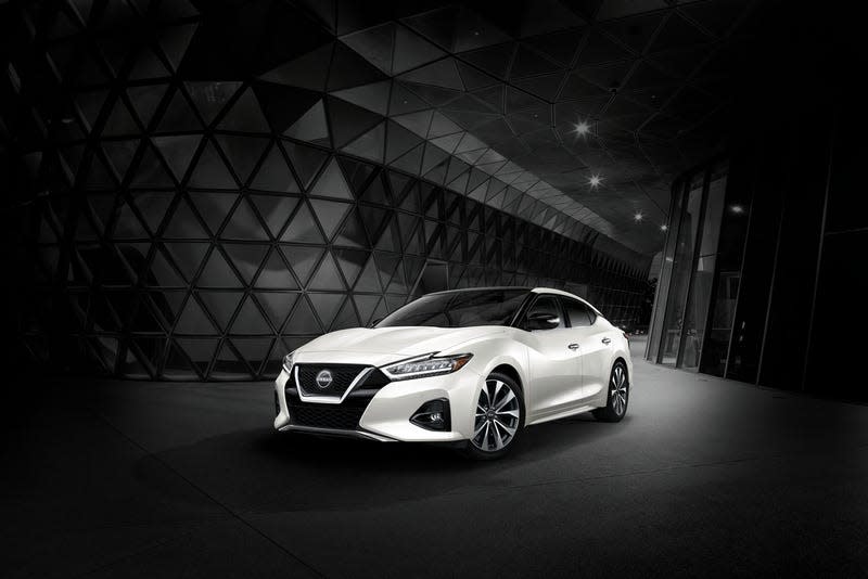 A white Nissan Maxima in a weird futuristic black room with lots of triangles