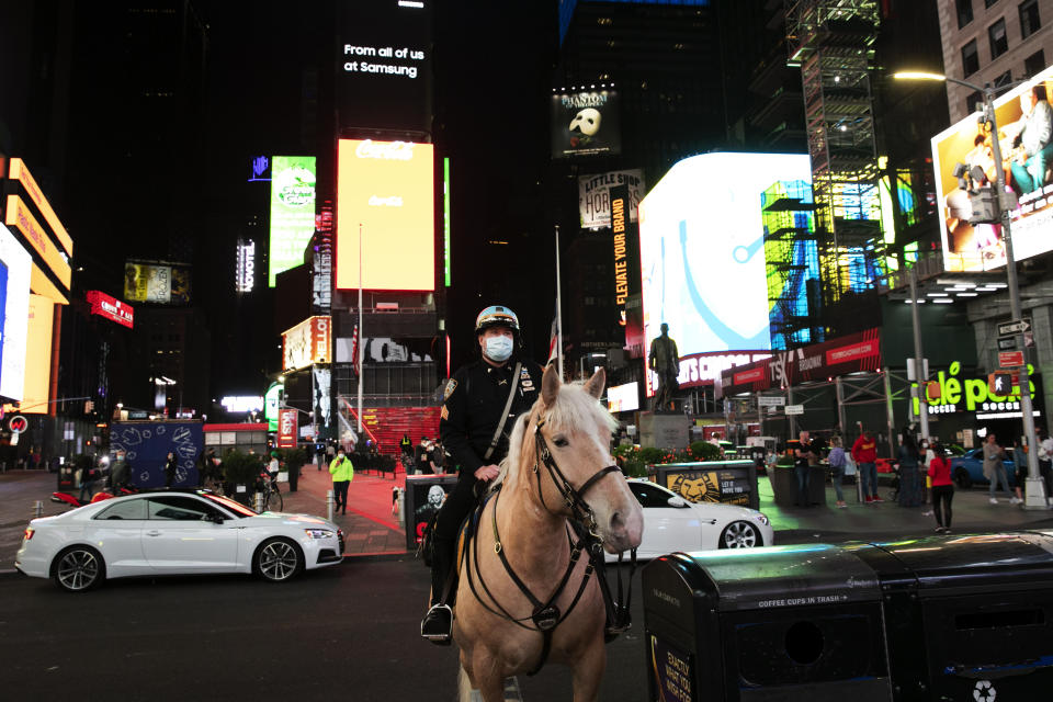 In this Saturday, May 2, 2020 photo, a New York City mounted police officer is posted in Times Square to keep an eye on parades of sports cars and motorcycles cruising through during the coronavirus pandemic. (AP Photo/Mark Lennihan)