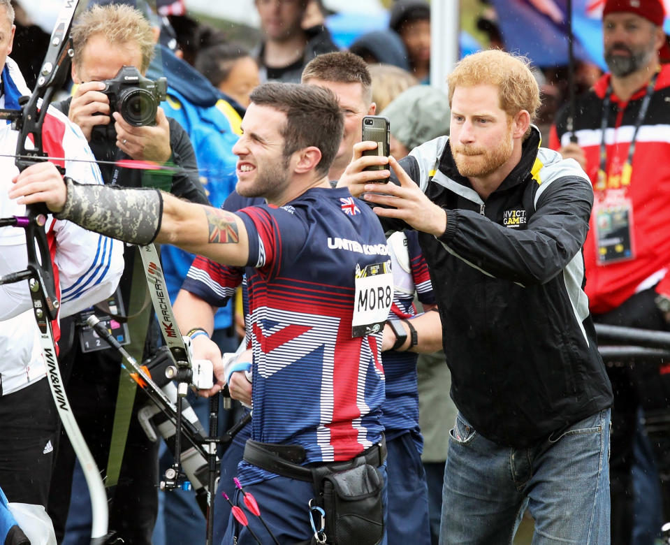 <p>Prince Harry gets up close and personal with a Team United Kingdom competitor in order to get the perfect shot at the archery competition during the 2017 Invictus Games in Toronto, Canada.</p>