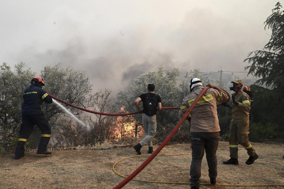 Firefighters and volunteers try to extinguish a wildfire in the town of Nea Anchialos, near Volos city, central Greece, Thursday, July 27, 2023. Wildfires caused explosions at an air force ammunition dump in central Greece on Thursday that had been safely evacuated in advance, as strong gusts of wind caused flare-ups around the country. (Tatiana Bolari/Eurokinissi via AP)