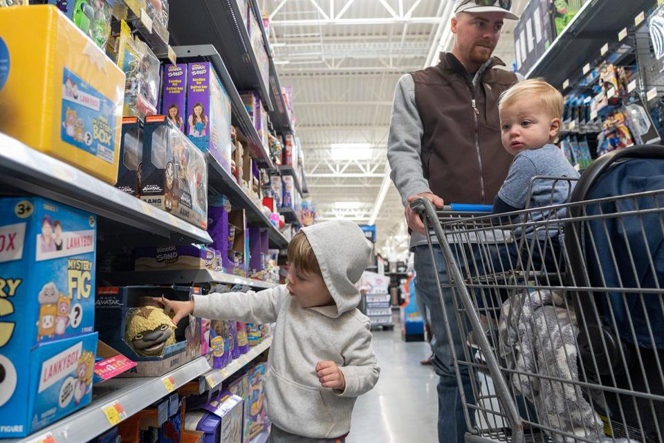 Layson Collins, 2, picks out a toy alongside his father and brother, Chandler Collins and Daxsyn Collins, 1, as they shop for early Black Friday deals at Walmart in Austin, Texas. Walmart is offering Black Friday deals throughout November.