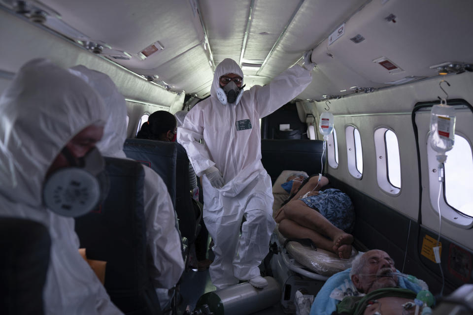 La enfermera Janete Vieira (centro) y el médico Daniel Siqueira monitorean a pacientes con COVID-19 a bordo de un avión durante su traslado desde Santo Antônio do Içá a un hospital en Manaos, Brasil, el 19 de mayo de 2020. El coronavirus se ha propagado río arriba hasta aldeas remotas y territorios indígenas donde para infectar a las tribus que viven allí. (AP Foto/Felipe Dana)