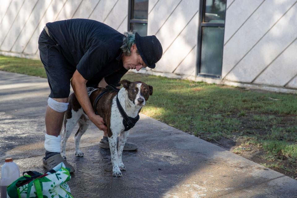 Jordan Klein cares for his dog, Max, outside the cooling center at Demuth Community Center in Palm Springs.