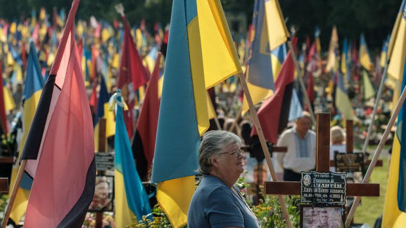 Una mujer en un cementerio ucraniano rodeada de banderas.
