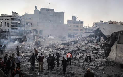 Palestinians gather at the site devastated after an Israeli airstrike hit a five-storey building in the Gaza Strip in response to rockets said were fired towards the country - Credit: Analdolu