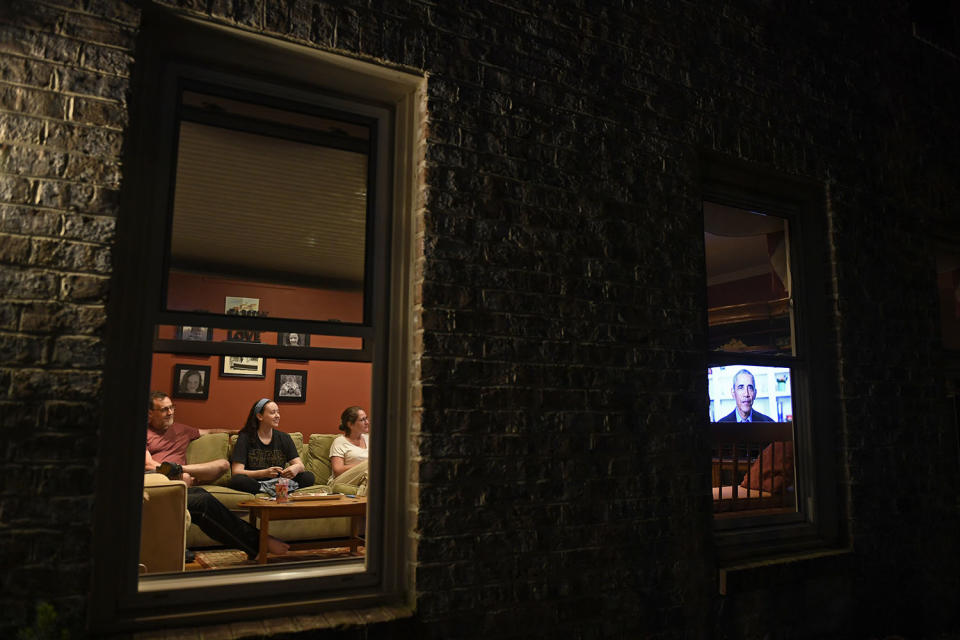 South River High School senior Isabel McGuire, center, is flanked by her parents as they watch former President Barack Obama address the high school Class of 2020 on television in their home in Maryland on Saturday.