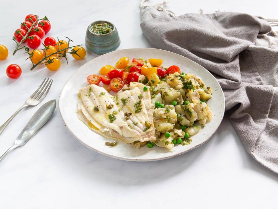 Lemon sole with peas, mint and crushed potatoesServes 2100g fresh peas (in pods) 180g heritage cherry tomatoes 1 lemon 20g capers 2 spring onions 2 tbsp oil 2 x 150g lemon sole fillet (skin on) 400g baby white potatoes Large handful of flat-leaf parsley Medium handful of fresh mintBoil a kettle. Roughly chop the spring onions and slice the cherry tomatoes in half. Remove the peas from their pods and cut the baby potatoes into quarters.Place the potatoes in a large saucepan. Cover with boiling water and boil for 15-20 minutes until softened. In the last 2 minutes of cooking, add in the fresh peas to the boiling water with the potatoes, then drain and keep warm.Meanwhile, make the salsa verde; finely chop the parsley leaves, mint leaves and roughly chop the capers. Place in a bowl with the juice from the lemon and 1 tablespoon of olive oil. Season with sea salt and black pepper.Heat a frying pan with half a tablespoon of oil on a medium heat and cook the spring onions and tomatoes for 3 minutes until softening. Remove from the pan and set aside.Using a sheet of kitchen roll dab the lemon sole dry then season the flesh side of the fish with a pinch of sea salt and black pepper. Heat the same frying pan with half a tablespoon of oil on a medium heat and cook the lemon sole flesh side down, (skin side up) for 5 mins until golden and cooked through. Turn off the heat and leave in the pan until ready to serve.Lightly crush the potatoes and peas with a fork. Stir through half of the salsa verde.Spoon the crushed potatoes onto two warm plates and top with the lemon sole. Serve alongside the tomatoes. Drizzle over the remaining salsa verde.Recipe from Mindfulchef.com