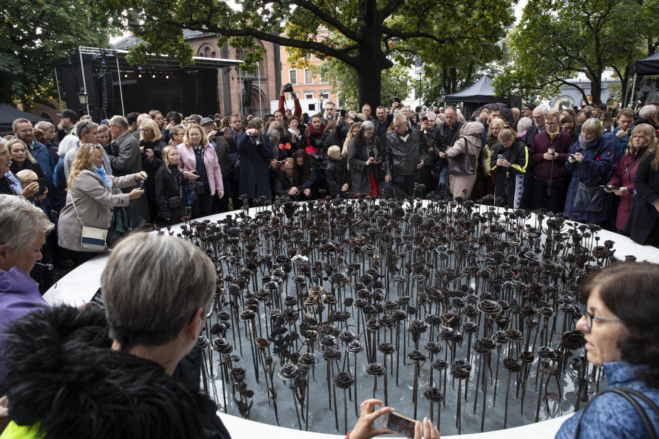 FILE - In this Saturday, Sept. 28, 2019 file photo, people look at the newly unveiled memorial "Iron roses" is unveiled outside Oslo Cathedral, in Oslo. The memorial is in memory of the 77 people who lost their lives on July 22, 2011 during a bombing and shooting attacks. At 3.25 p.m. on July 22, 2021, a ray of sun should have illuminated the first of 77 bronze columns on a lick of land opposite Utoya island outside Oslo. Over the next 3 hours and 8 minutes, it would have brushed each column in turn, commemorating every person killed by right-wing terrorist Anders Breivik. But on the ten-year anniversary of the terror, the memorial remains a construction site. (Terje Bendiksby/NTB Scanpix via AP, File)