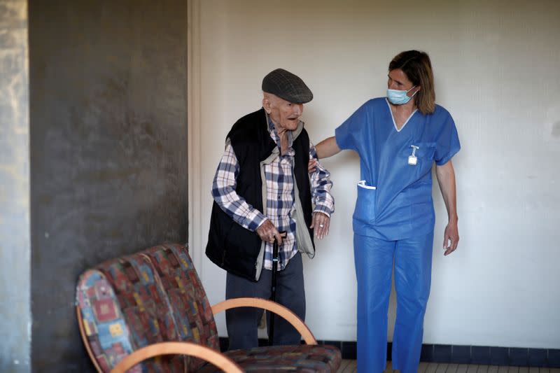 A member of the medical staff walks with a resident at the Emile Gerard retirement home (EHPAD) in Livry-Gargan