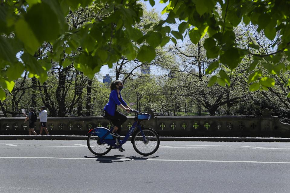 A cyclist wearing a protective mask passes people in Central Park Saturday, May 2, 2020, in New York. New York City police dispatched 1,000 officers this weekend to enforce social distancing due to coronavirus concerns, as warmer weather tempted New Yorkers to come out of quarantine. Officers set out on foot, bicycles and cars to break up crowds and remind everyone of public health restrictions requiring they keep 6 feet away from others.(AP Photo/Frank Franklin II)