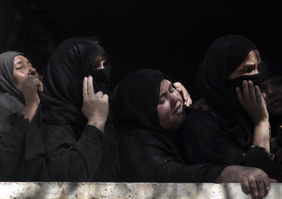 Relatives of Ahmed Abu Lebdeh, 22, who was killed by Israeli troops during Friday's protest at the Gaza Strip's border with Israel, look at mourners carry his body out of the family home during his funeral in town of Khan Younis, southern Gaza Strip, Saturday, Oct. 27, 2018. (AP Photo/Khalil Hamra)