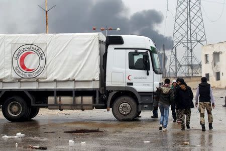 Rebel fighters walk near Red Crescent vehicles on their way to al Foua and Kefraya, in Idlib province, Syria January 11, 2016. REUTERS/Ammar Abdullah