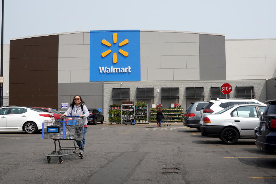 A shopper pushes a cart in a Walmart parking lot.