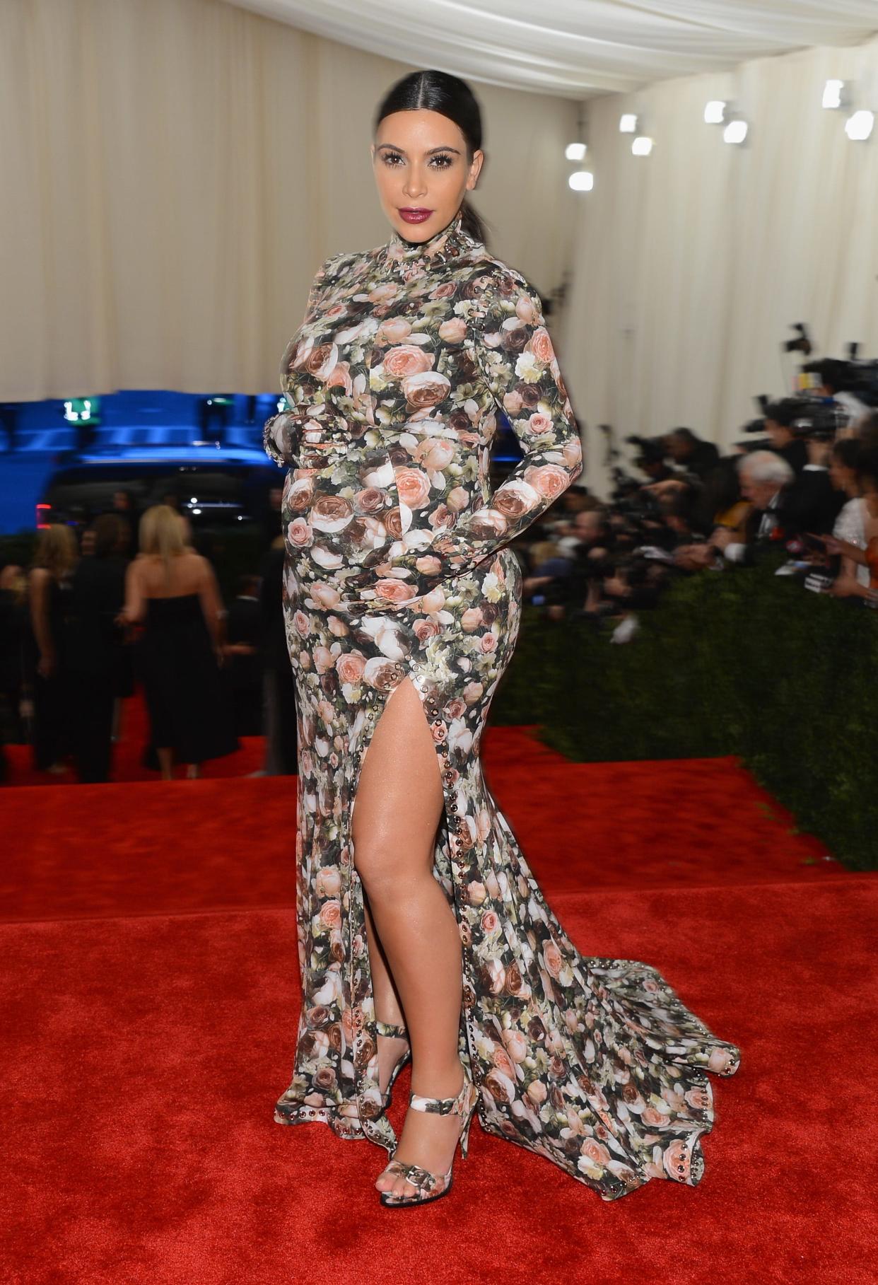 Kim Kardashian attends the 2013 Met Gala. She's pregnant and wearing a floral gown with a thigh-high slit.
