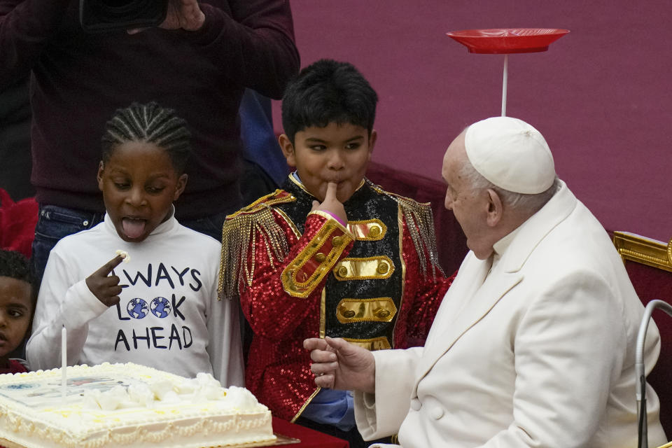 Pope Francis looks at children as they taste a cake he was offered to celebrate his birthday with children assisted by the Santa Marta dispensary during an audience in the Paul VI Hall, at the Vatican, Sunday, Dec. 17, 2023. Pope Francis turnes 87 on Dec.17. (AP Photo/Alessandra Tarantino)