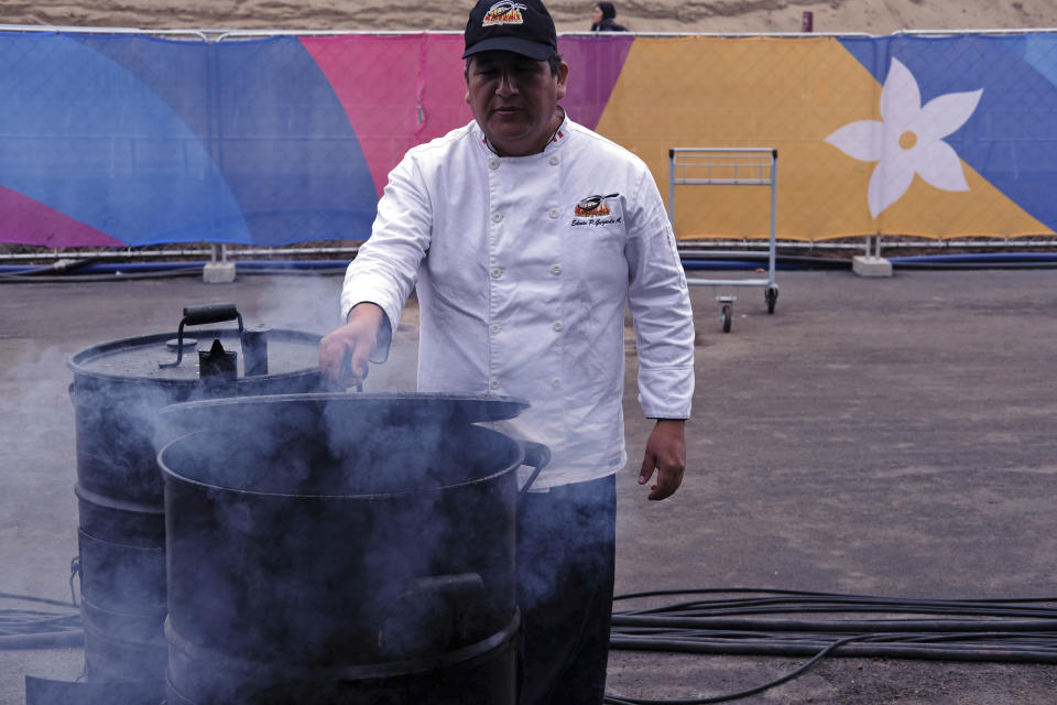 In this Aug. 8, 2019 photo, chef Edwin Guzman of the Estilo y Sabor catering house poses for photos cocking "chancho al cilindro", or pork roasted in an oil drum at the international center outside the Pan American athletes' village in Lima, Peru. Peruvian food was the star at the recent Pan Am Games held in Latin America’s culinary capital. Athletes from countries across the Americas tasted the highly-regarded cuisine that blends indigenous traditions with European, African and Asian influences with an abundance of seafood from the Pacific Ocean’s cold Humboldt current. (AP Photo/Luis Andres Henao)