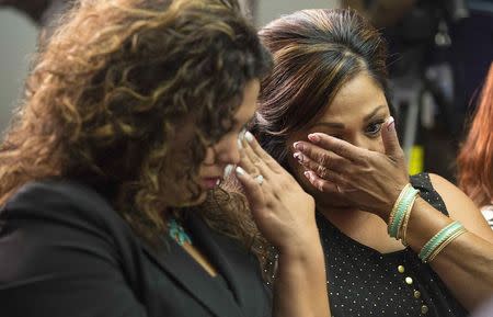 Rosie Cortinas (L) and Monica Coronado, who are family members of General Motors crash victims, wipe their eyes as Kenneth Feinberg, a victims compensation lawyer hired by General Motors, speaks in Washington June 30, 2014. Feinberg was speaking at a news conference to announce the eligibility criteria for a program to compensate victims of a faulty ignition switch that prompted the recall of 2.6 million vehicles. REUTERS/Joshua Roberts