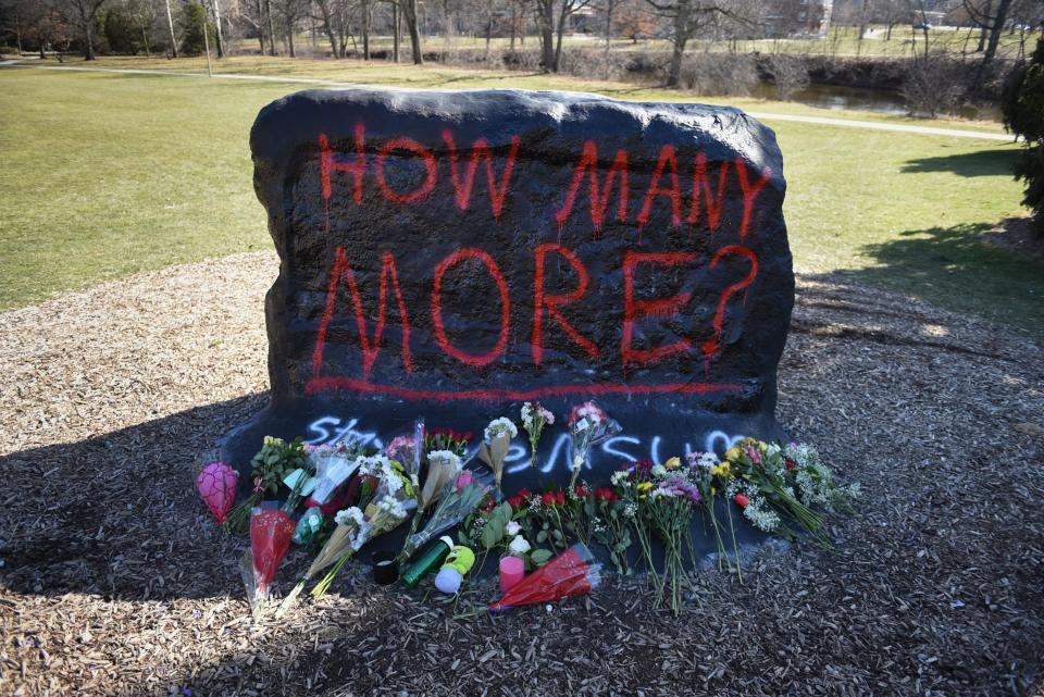 Flowers were left at the base of "The Rock" on the campus of Michigan State University, Tuesday, Feb. 14, 2023, to honor the victims of Monday's shooting on campus. Students use "The Rock" as a canvas where students paint messages for the campus. Following the Feb. 13, 2023, mass shooting that killed three and wounded five people, it now reads, "How many more? Stay safe MSU."