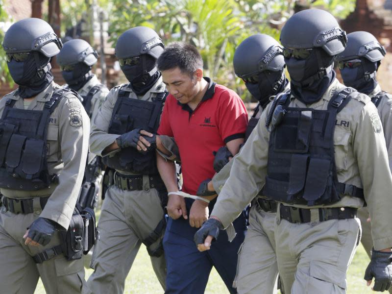 Andrew Chan wird von vermummten und schwerbewaffneten Polizisten ins Nusakambangan-Gefängnis gebracht, wo ein Erschießungskommando auf ihn wartet. Foto: Made Nagi/Archiv