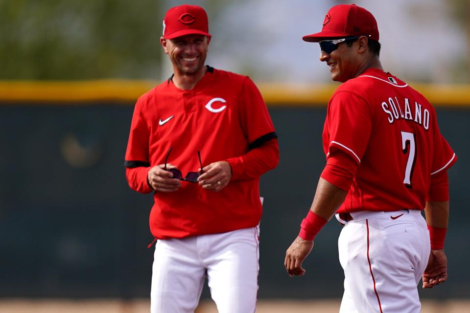 Cincinnati Reds infielder Donovan Solano (7) shares a laugh with outfield coach Jeff Picker during base-running workouts, Saturday, March 19, 2022, at the team's spring training facility in Goodyear, Ariz.