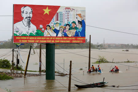 People recover motorbikes from a flooded fields while the Doksuri storm hits in Ha Tinh province, Vietnam September 15, 2017. REUTERS/Kham