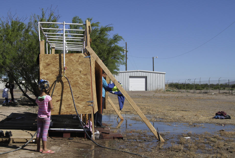 CORRECTS DAY - In this Wednesday, May 22, 2019, Migrants wait for a turn at a cold shower in a shelter set up by city officials in Deming, N.M. A surge of asylum-seeking families has been straining cities along the southern U.S. border for months, but now the issue is flowing into cities far from Mexico, where immigrants are being housed in an airplane hangar and rodeo fairgrounds and local authorities are struggling to keep up with the influx. (AP Photo/Cedar Attanasio)