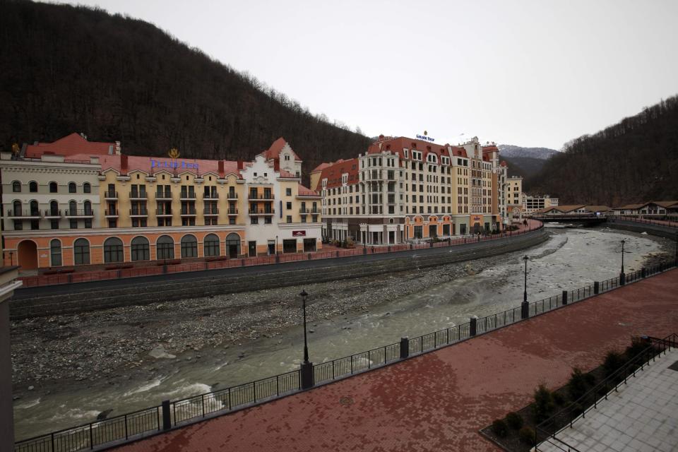 ILE - In this Feb. 22, 2013 file photo, newly built hotels are situated along a river in Krasnaya Polyana, mountain Olympic cluster, 60 kilometers East from Sochi, Russia. For visitors to the Winter Olympics, Sochi may feel like a landscape from a dream. Palm trees evoke a tropical seaside resort, but the Black Sea itself is seriously cold; turn away from the palms and the jagged, snow-covered peaks of the Caucasus Mountains rise nearby. (AP Photo/Alexander Zemlianichenko, file)