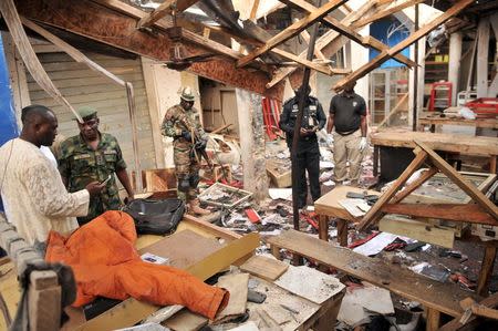 Soldiers and policemen are pictured at the scene where two female suicide bombers blew themselves up at a mobile phone market in the northern Nigerian city of Kano November 18, 2015. REUTERS/Stringer