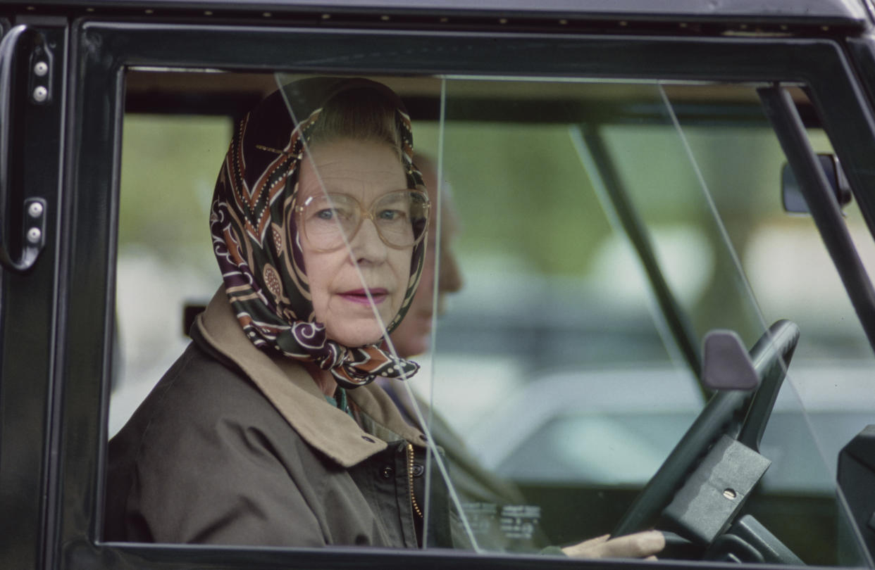 British Royal Queen Elizabeth II, wearing a headscarf and a waxed jacket, driving a Land Rover Defender at the Royal Windsor Horse Show, held at Windsor Home Park in Windsor, Berkshire, England, 12th May 1989. (Photo by Tim Graham Photo Library via Getty Images)