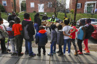 In this March 29, 2020, photo, volunteers India Blocker-Ford, center, D.J. Wood, left, and Regina Summers, right, sort donated bags of hot meals while children wait for the food to be distributed in southeast Washington. Neighborhood deliveries are part of a new Martha's Table initiative, along with community partners, to get needed food directly to the neighborhoods they serve. Local volunteers are the tip of the spear for a grassroots community effort to keep Washington's most vulnerable neighborhoods fed during the unprecedented coronavirus crisis which has nearly shut down the American economy. (AP Photo/Jacquelyn Martin)