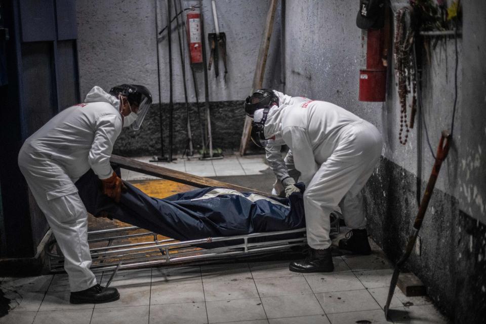 El personal de Iztapalapa maniobra para poner colocar la bolsa que contiene el cuerpo de una víctima del coronavirus en el interior del horno crematorio. (Photo by PEDRO PARDO/AFP via Getty Images)