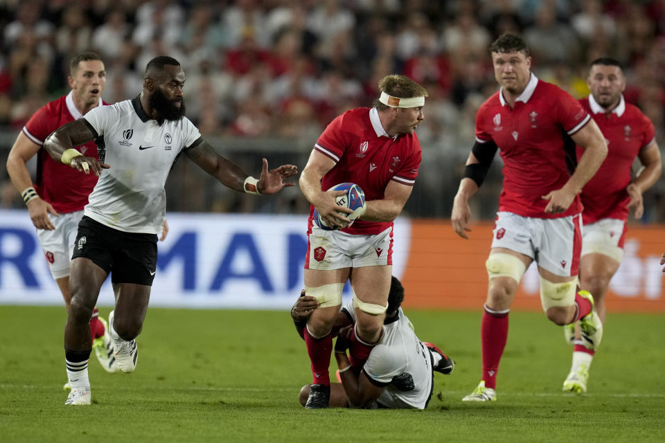 Wales' Aaron Wainwright, center, is tackled by Fiji's Ilaisa Droasese during the Rugby World Cup Pool C match between Wales and Fiji at the Stade de Bordeaux in Bordeaux, France, Sunday, Sept. 10, 2023. (AP Photo/Themba Hadebe)