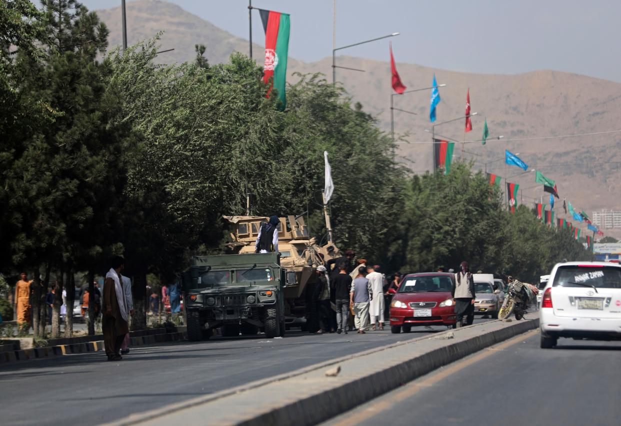 Taliban fighters stand guard on the road leading to the Hamid Karzai International Airport, in Kabul, Afghanistan on Monday, Aug. 16, 2021.