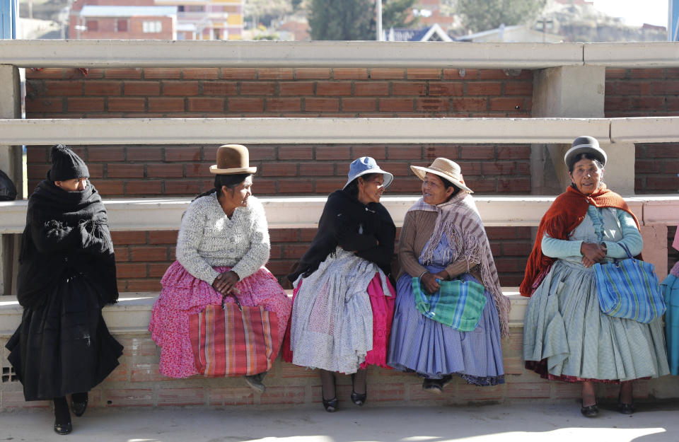 Women sit outside a polling station during general elections in La Paz outskirts, Bolivia, Sunday, Oct. 20, 2019. Bolivians are voting in general elections Sunday where President Evo Morales is Presidential candidate for a fourth term. (AP Photo/Jorge Saenz)