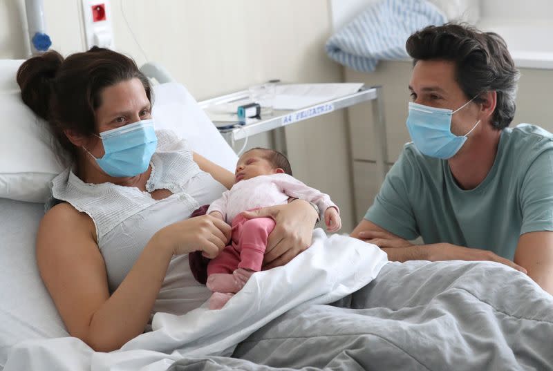 Amandine, who tested positive for the coronavirus disease (COVID-19) just before giving birth, and Francois, wearing protective face masks, are pictured with their newborn daughter Mahaut at the maternity at CHIREC Delta Hospital in Brussels
