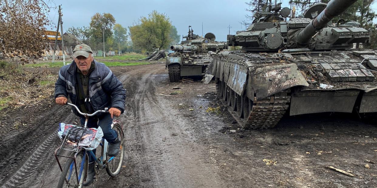 A local resident rides a bicycle past abandoned Russian tanks in the village of Kurylivka, amid Russia's attack on Ukraine, in Kharkiv region, Ukraine October 1, 2022.