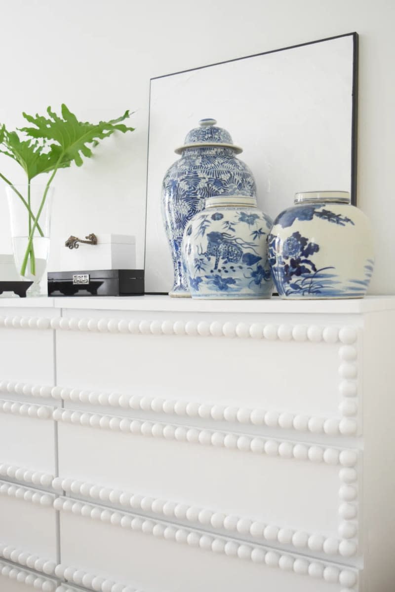white dresser with round button details on drawers and blue and white ceramic vases